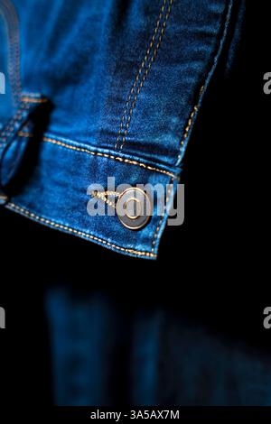 Eine detaillierte Nahaufnahme des Knopfs an einer blauen Jeans, die das Design und die Handwerkskunst unterstreicht. Ideal, um Details in Mode zu betonen Stockfoto