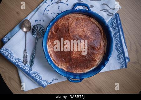 Hüttenkäseauflauf in einer blauen Schüssel auf einem Holztisch Stockfoto