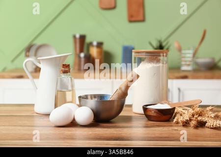 Frische Eier, Mehl, Backpulver und Öl auf Holztisch in der Küche Stockfoto