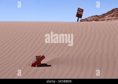Sanddünen mit strukturierter Oberfläche und roten Schildern klettern nicht, was den Umweltschutz und den verantwortungsvollen Tourismus in der Wüste von Atacama unterstreicht. Stockfoto