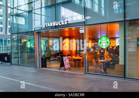 Starbucks Café mit Gästen am frühen Morgen am Hauptbahnhof von den Haag, Niederlande Stockfoto