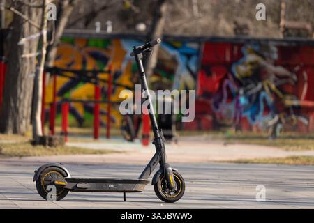Eine lebendige Straßenszene mit einem Elektroroller vor einem farbenfrohen Stadtbild, das perfekt das Wesen des modernen Verkehrs und einfängt Stockfoto