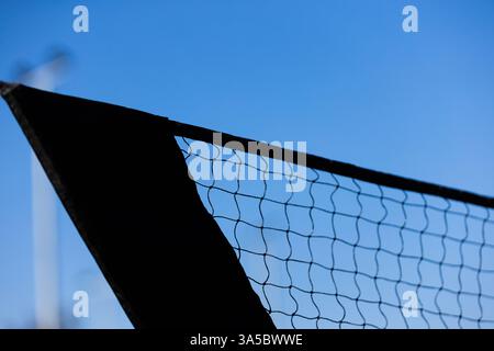 Nahaufnahme eines Sportnetzes vor einem klaren blauen Himmel, der die verwobene Struktur und das Material des Netzes in Silhouette-Stil zeigt Stockfoto