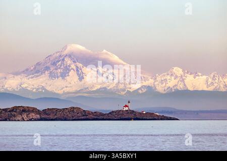 Blick auf den Trial Islands Lighthouse mit dem schneebedeckten Mount Baker im Hintergrund - Victoria, Vancouver Island, British Columbia, Kanada Stockfoto