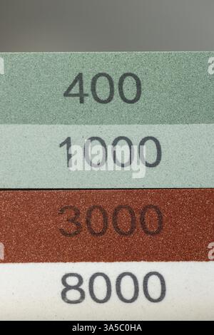 Nahaufnahme dunkler Hintergrund auf dem Tisch liegt rot und grün Ausrüstung ein Set zum Schärfen und Polieren von Küchenmessern und verschiedenen Klingen unterschiedlich Stockfoto