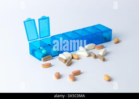 Weißer Hintergrund zwei hellblaue Pillenboxen mit einem Paar geöffneter Deckel für die Einnahme von Pillen, Gesundheitspflege, teilweiser Füllung, verschiedenen Formen und Farben von Stockfoto