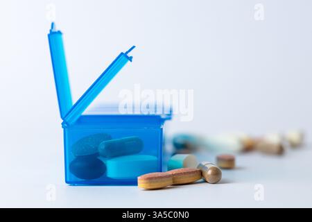 Nahaufnahme weißer Hintergrund zwei hellblaue Pillenboxen mit zwei offenen Deckeln für die Einnahme von Pillen, Gesundheitspflege, teilweises Füllen, verschiedene Formen Farben Stockfoto
