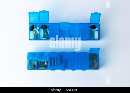 Top Shot auf weißem Hintergrund es gibt zwei hellblaue Pillenboxen mit ein paar offenen Deckeln für die Einnahme von Pillen, Gesundheitspflege, partielle Füllung, unterschiedlich Stockfoto