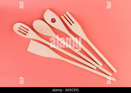 Nahaufnahme auf weichem rosa Hintergrund liegen neue Küchenhelfer Holzutensilien verschiedener Formen Spatel für Tephlon Beschichtung Naturholz handgefertigt Stockfoto