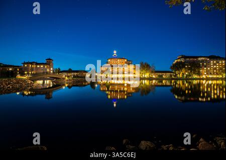 Elegantes Lakeside Hotel, das während der Sternennacht auf ruhigem Wasser reflektiert Stockfoto