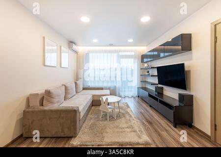 Helles und modernes Wohnzimmer mit minimalistischen Möbeln, Holzfußboden und gemütlicher Atmosphäre. Ideal für die Innenraumgestaltung, die die Kontemperierung betont Stockfoto