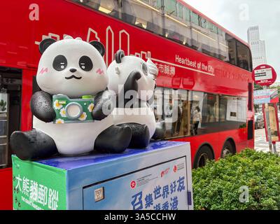 Zwei Panda-Statuen, die mit einer Kamera auf einem Kasten in Hongkong verziert sind, mit einem roten Doppeldeckerbus im Hintergrund. Stockfoto
