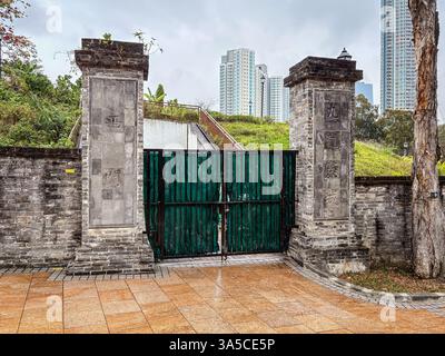 Eingangstor zum Stadtpark Kowloon mit Mauern und alten Backsteingebäuden und Gebäuden im Hintergrund. Stockfoto
