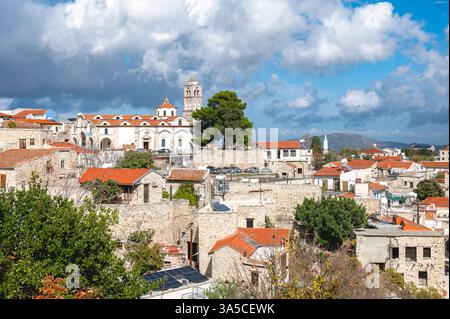 Kirche des heiligen Kreuzes dominiert die Skyline des Dorfes Pano Lefkara, mit traditionellen Steinhäusern und fernen Bergen unter einem bewölkten Himmel Stockfoto