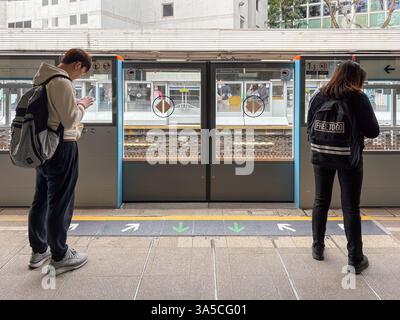 MTR-Bahnhof in Hongkong mit zwei Personen. Die Türen der U-Bahn sind geschlossen, wenn die Fahrgäste zur Verfügung stehen. Stockfoto