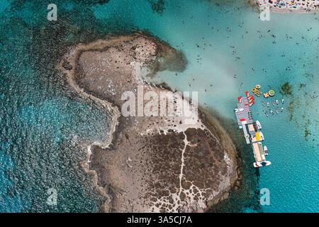 Aus der Vogelperspektive des berühmten Nissi-Strandes in Ayia Napa, Zypern, wo Touristen das kristallklare türkisfarbene Wasser genießen Stockfoto