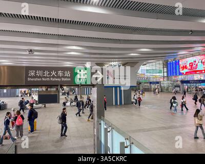 Innenansicht des Bahnhofs Shenzhen North. Umfasst das Ausstiegsschild, Pendler und digitale Anzeigetafeln. Stockfoto