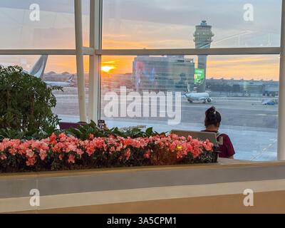 Blick auf den Sonnenaufgang auf den Asphalt und das Flugzeug vom Inneren des Hong Kong International Airport. Reiseszene und Fenstersitz. Stockfoto