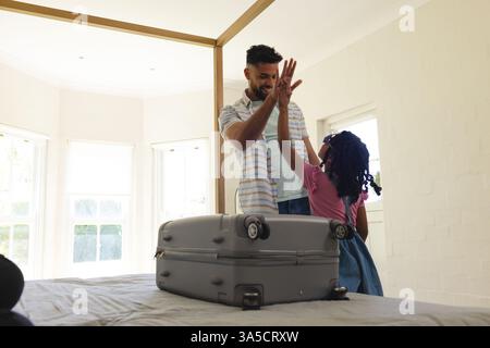 Vater und Tochter haben zu Hause den Koffer aufs Bett gepackt Stockfoto