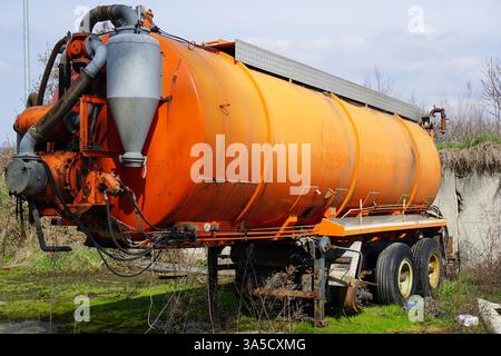 Ein alter, rostbedeckter Vakuumtankwagen zum Pumpen und Transportieren flüssiger Abfälle wie Abwasser oder Schlamm. Der abgenutzte Zustand der Anlage unterstreicht den langfristigen Einsatz in der industriellen oder kommunalen Abfallentsorgung. Das Bild repräsentiert das Konzept der Abwasserwirtschaft und der Umweltsanierung. Stockfoto