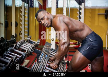 Schöner schwarzer Bodybuilder, der nach dem Training im Fitnessstudio ausgeruht ist und in die Kamera guckt Stockfoto