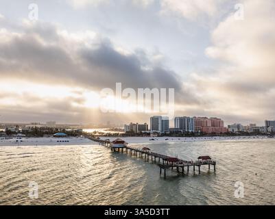 Pier 60 erstreckt sich bis in den Golf von Mexiko mit der Skyline von Clearwater Beach und Sonnenstrahlen, die durch Wolken brechen, Florida, USA. Stockfoto