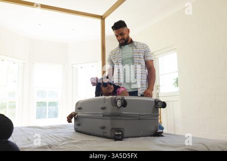 Vater und Tochter spielen zu Hause mit Koffern und genießen spielerische Bindungszeit Stockfoto