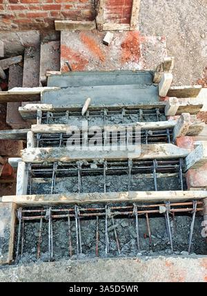 Stahlbetontreppen werden bei klarem Tageslicht auf einer Baustelle mit Holzstützen und Metallbewehrung geformt. Stockfoto