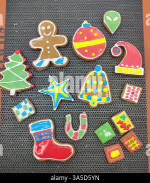 Eine Vielzahl von bunten, dekorierten Weihnachtskeksen auf einer strukturierten Oberfläche. Die Kekse sind geformt wie ein Lebkuchenmann, Weihnachtsbaum, Ornamente, A Stockfoto