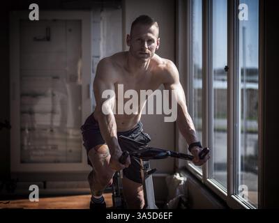 Attraktive junge Mann trainieren im Fitnessraum, spinning auf Heimtrainer Stockfoto