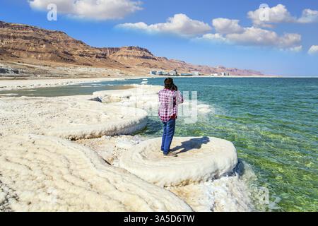 Eine Frau in einem karierten Cowboyhemd fotografiert die Meeresoberfläche. Verdunstetes Salz bildet schöne Kristalle auf der Wasseroberfläche. Der salzreichste See in der Stadt Stockfoto