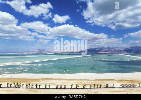 Herrliches Totes Meer. Das Wasser reflektiert das helle Blau des Himmels. Der von Palmen gesäumte Haghway verläuft entlang der Küste. Aufnahmen von Drohnen. Ungewöhnlich b Stockfoto