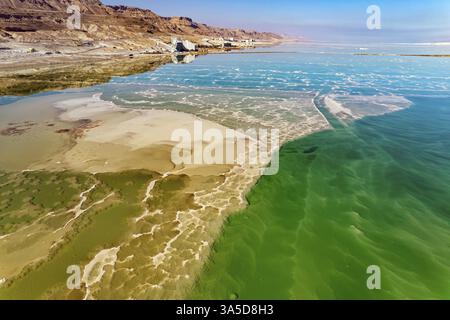 Das klare grüne Wasser des salzigen Meeres ist von rosa Bergen umgeben. Auf dem Meeresboden sind Salzablagerungen sichtbar. Magie des Toten Meeres. Das Foto war Stockfoto