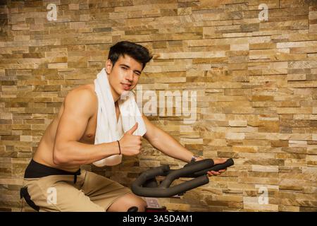 Attraktive junge Mann trainieren im Fitnessstudio: Spinnen auf Heimtrainer Stockfoto