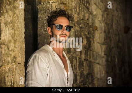 Gut aussehender, fitter Mann, der auf einer alten Ziegelstraße in der italienischen Stadt steht. Horizontale Außenaufnahme Stockfoto