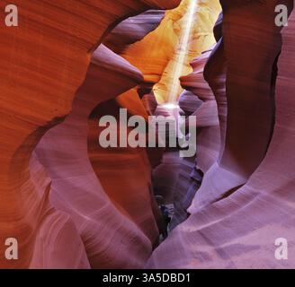 Ein dünner Sonnenstrahl beleuchtet den sandigen Boden des Canyons. Mittags in einem rot-orangen Antelope Canyon Stockfoto