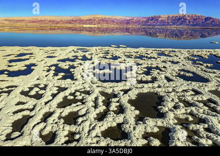 Totes Meer. Das blaue Wasser ist von rosa Bergen umgeben. Sonniger Wintertag. Das Bild wurde von einer Drohne aus der Vogelperspektive aufgenommen. Verdampftes Salz bildet sich Stockfoto