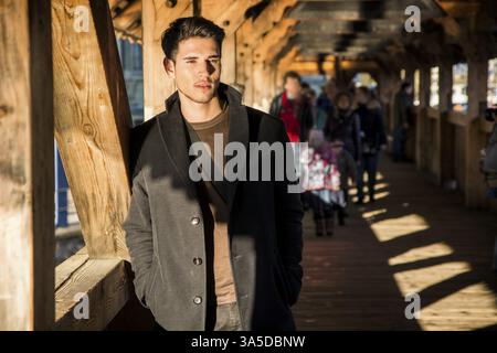 Jungen dunkelhaarigen Mann stehend auf mittelalterlichen Holzsteg in der Schweiz während wegschauen Stockfoto