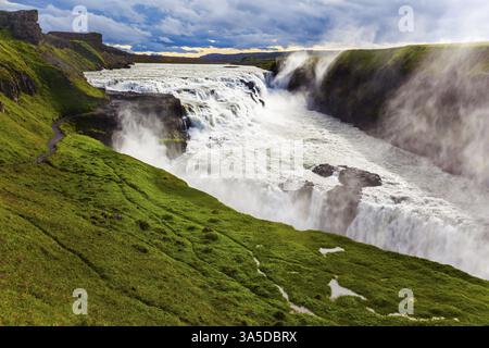 Wassernebel fliegen über Wasserfälle. Riesige Wassermassen stürzen in den Abgrund. Fantastisch malerischer Wasserfall in der isländischen Tundra - Gullfoss. Der Tiefenbereich Stockfoto
