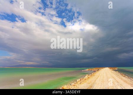 Niedrige Winterwolken spiegeln sich im grünen Meerwasser. Wintergewitter beginnt. Das malerische Tote Meer. Israel Stockfoto