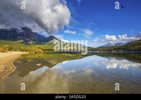 Pyramid Mountain und herrliche Cumulus Wolken spiegeln sich im glatten Wasser des Pyramid Lake. Morgens in den Rocky Mountains, Kanada, Nordamerika Stockfoto