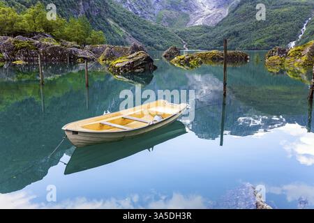 Wunderschönes bergiges Norwegen. Der Bergsee Bondhuswatnet. Das malerische kleine Boot liegt unweit der Küste vor Anker. Das Boot wird im cl reflektiert Stockfoto