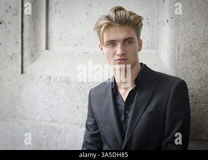 Attraktive blonde Jüngling in Hemd und Jacke, gegen Wand Stockfoto
