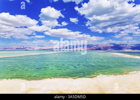 Malerisches Totes Meer. Heller Märztag. Das Wasser reflektiert das helle Blau des Himmels. Üppige Kumuluswolken spiegeln sich im Wasser. Aufnahmen von Drohnen Stockfoto