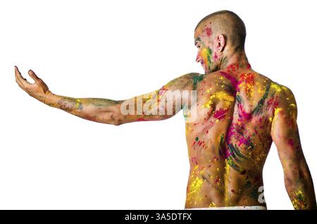 Hübscher junger Mann von hinten mit Haut alle gesehen gemalt mit Holi Farben, isoliert auf weißem Hintergrund, Arm ausgestreckt Stockfoto