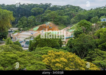 Singapur City, Singapur, 22. Januar 2019: Aus der Vogelperspektive der aktiven Baustelle mit Baggerladern und anderen Geräten umgeben von üppig grünen Bäumen Stockfoto
