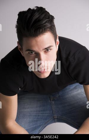 Hübscher junger Mann sitzend, gesehen von oben, Blick in die Kamera Stockfoto