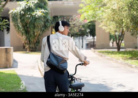 Fahrradfahren und Stadtbesichtigung. Ein junger Mann fährt mit dem Fahrrad und hört Musik im Freien. Stockfoto