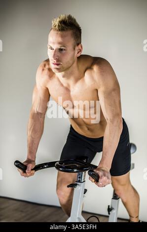Attraktive junge Mann trainieren im Fitnessraum, spinning auf Heimtrainer Stockfoto