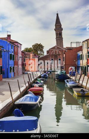 Bunte Häuser und Kippturm spiegeln sich im Wasser der Kanäle wider. Insel Burano in der Nähe von Venedig. Die Boote parken am Ufer. Der Kontra Stockfoto
